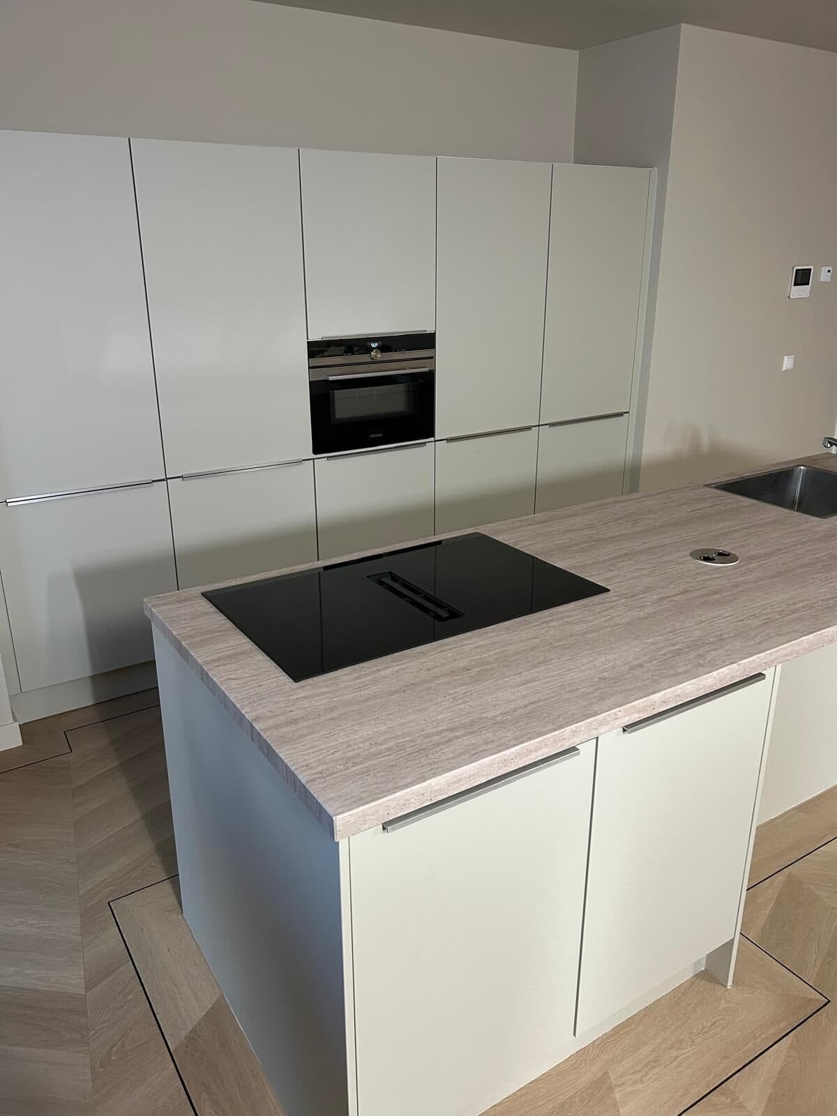 Lichte keuken met kookeiland in steenlook en visgraat vloer