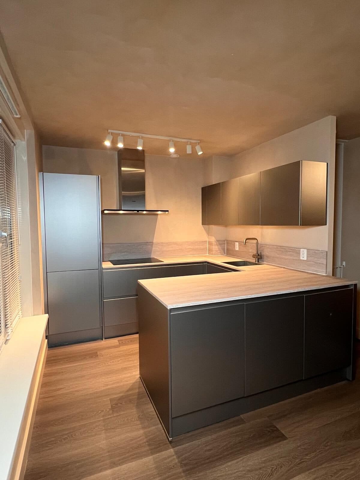 Mat zwarte keuken met houtlook werkblad en messing kraan